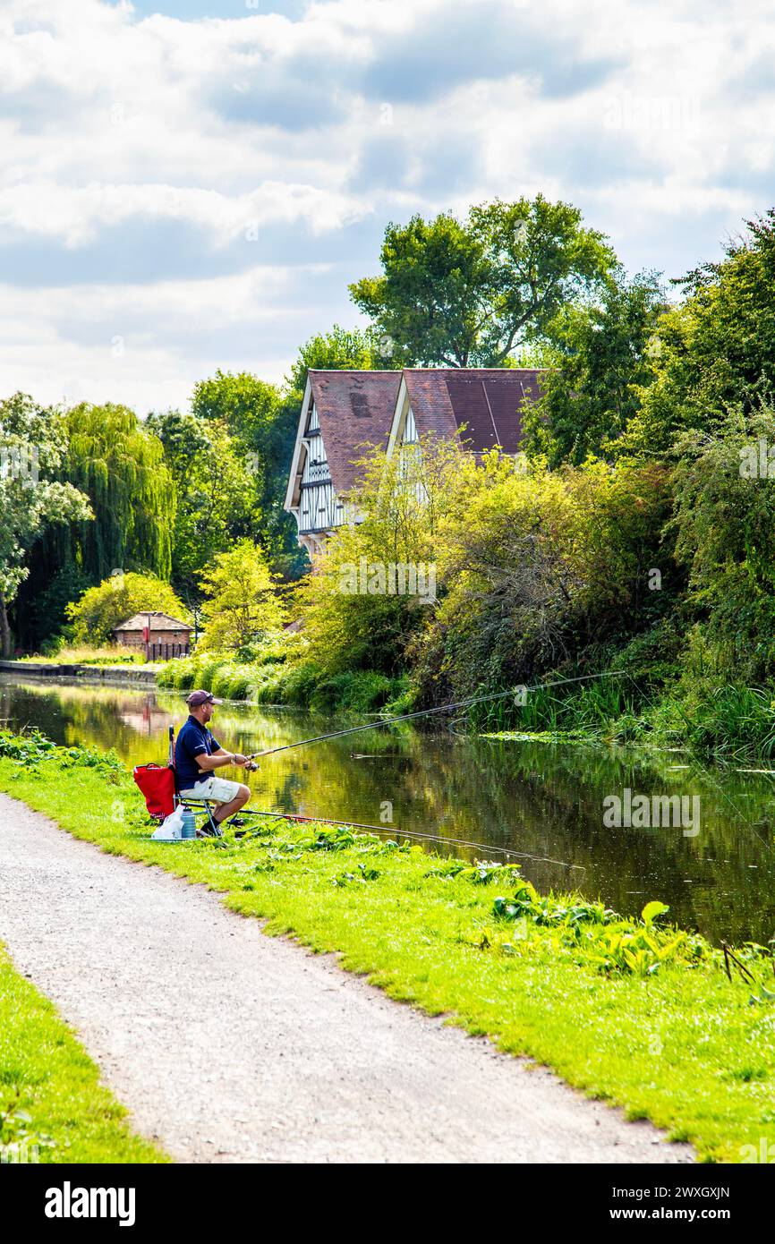 Man fishing in the River Lee Navigation Canal and the The Navigation Harvester restaurant in background, Enfield, London, UK Stock Photo