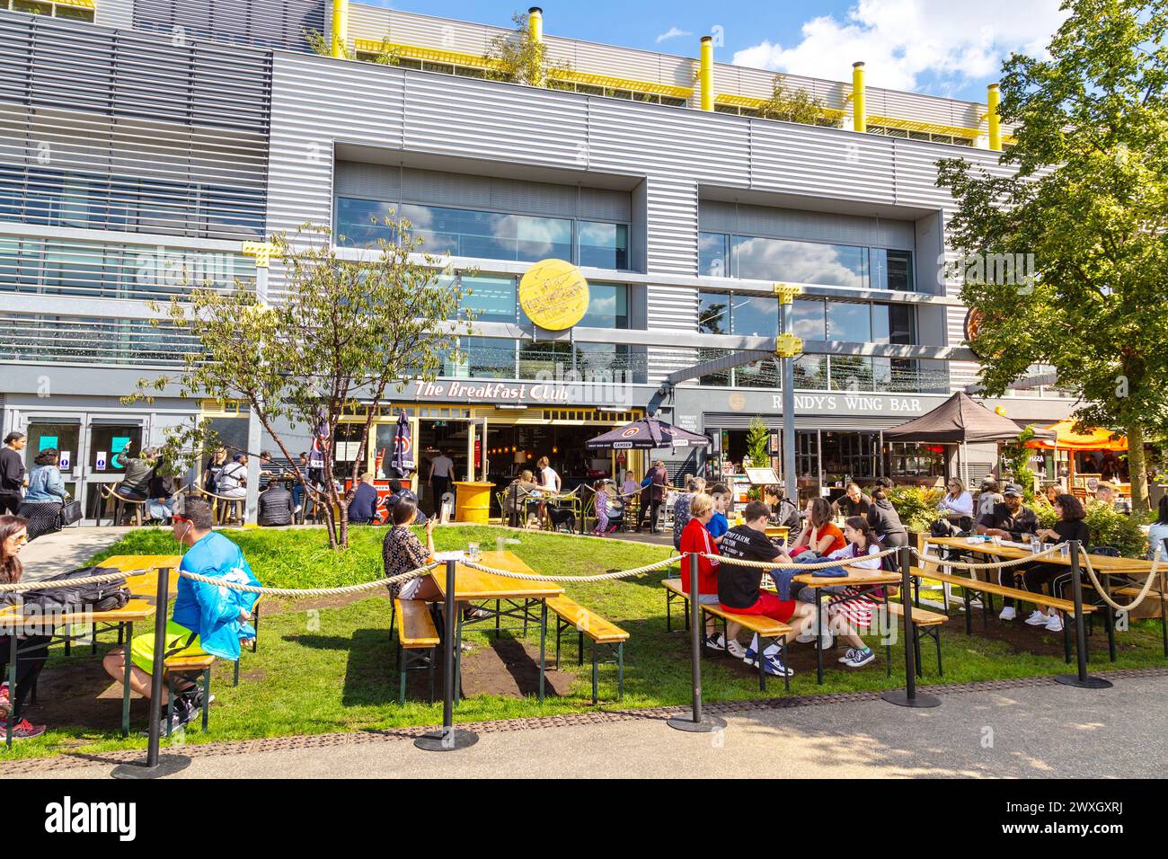 People eating outdoors at restaurants in Here East along the River Lee Navigation canal, Olympic Park, Stratford, London, England Stock Photo