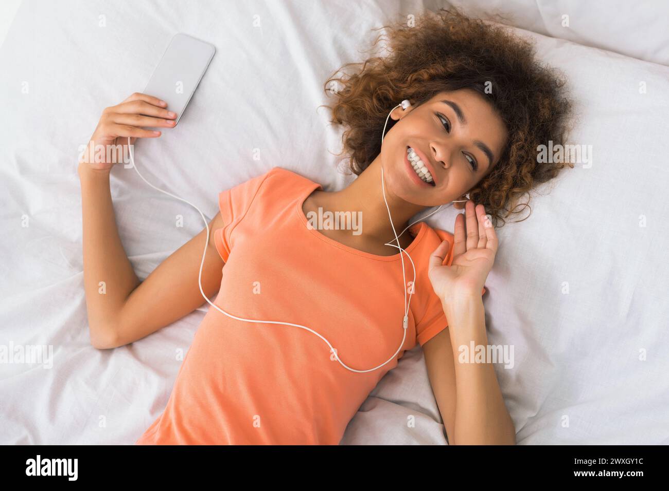 Young woman resting in bed with smartphone Stock Photo