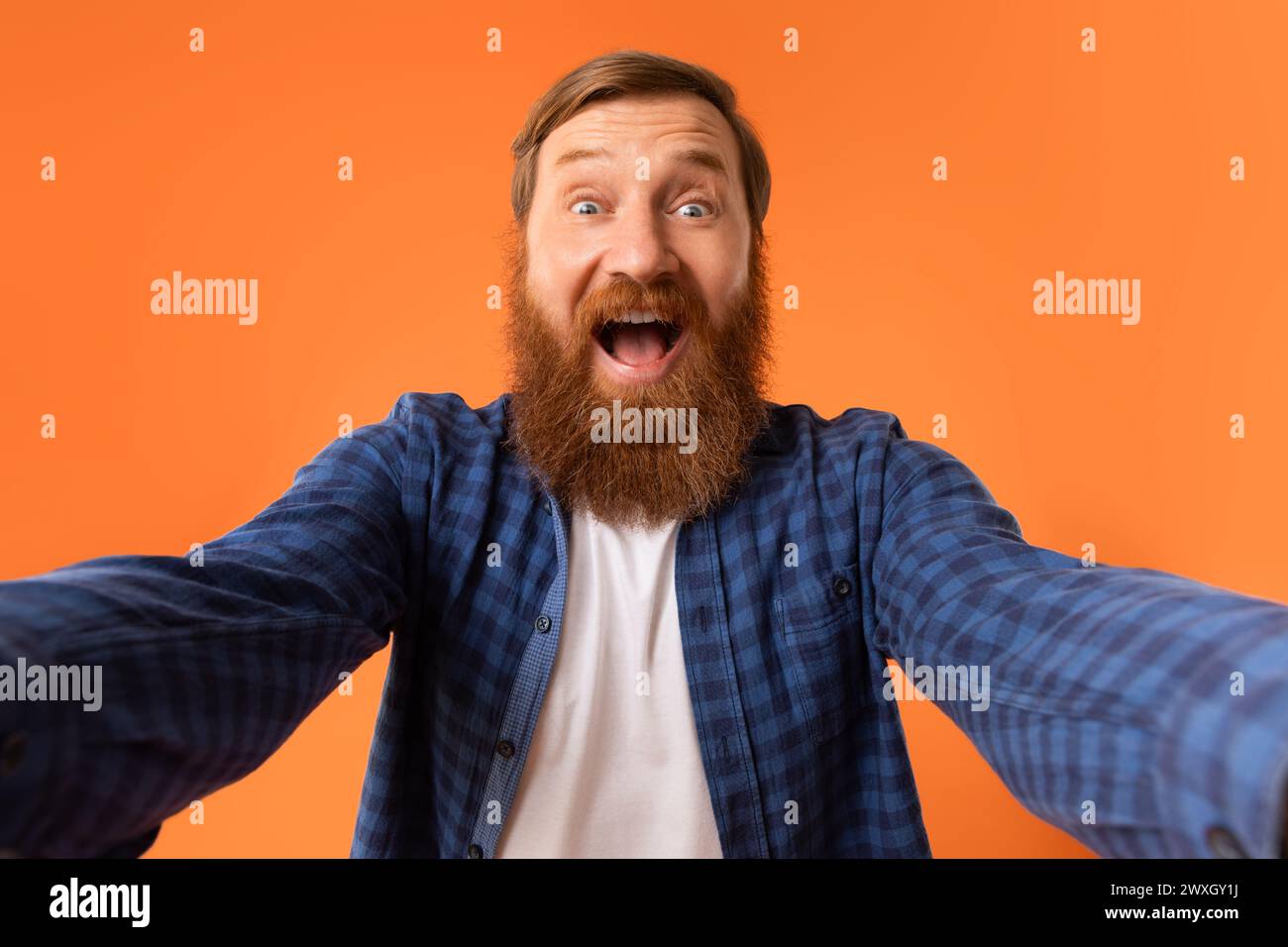 Excited Man With Red Beard Shouting Spreading Hands, Orange Background Stock Photo