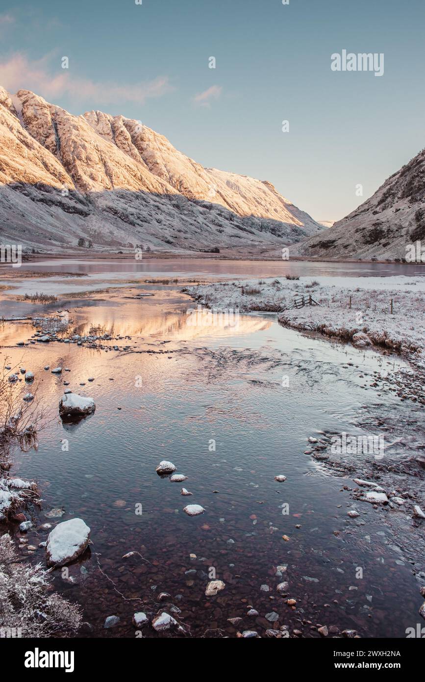 Snow-covered mountains in Glencoe reflect in the waters of Loch Achtriochtan in the Scottish Highlands Stock Photo