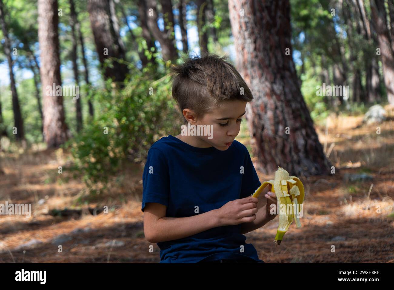 Child eating a banana in the forest Stock Photo