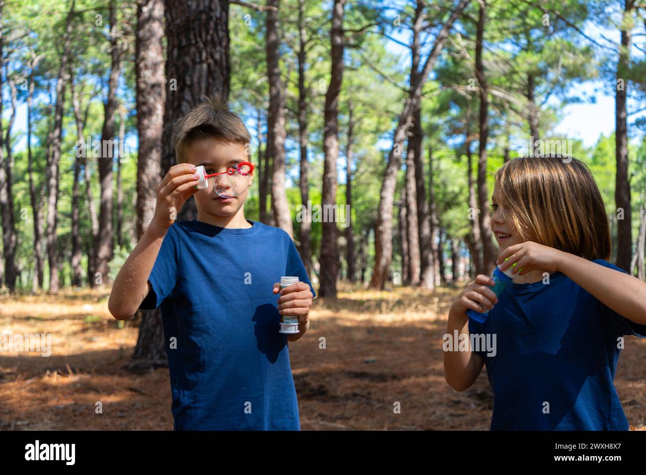 Two children playing in nature with soap bubbles Stock Photo - Alamy