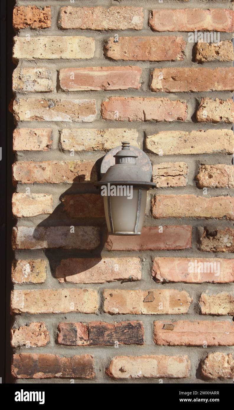 A small lamp illuminates a brick wall next to a fireplace Stock Photo