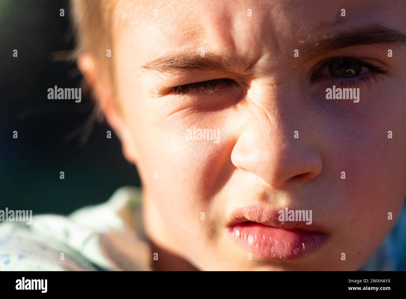 Portrait of a boy winking at the sun Stock Photo