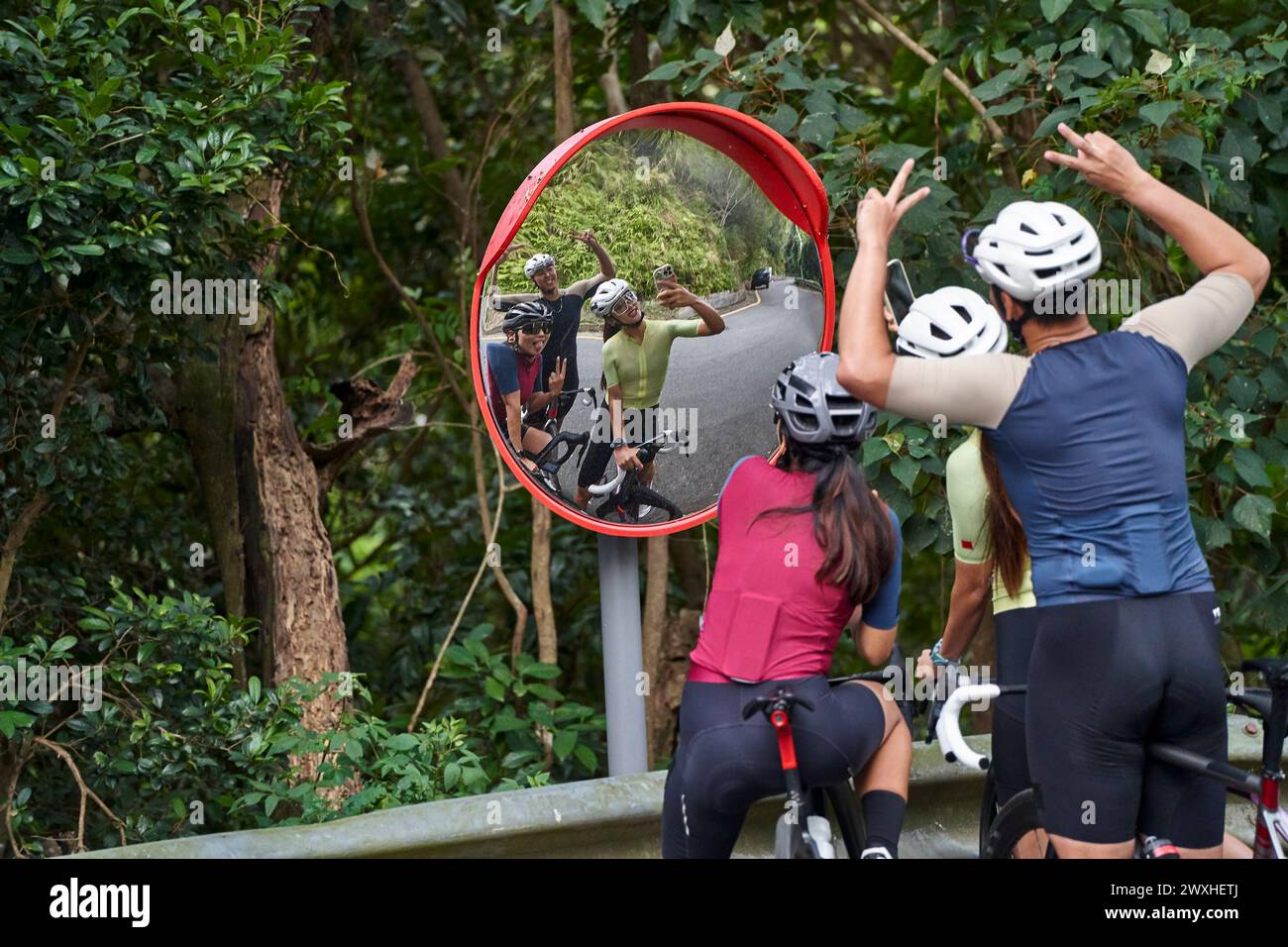 group of three young asian cyclists taking a funny selfie together outdoors on rural road Stock Photo