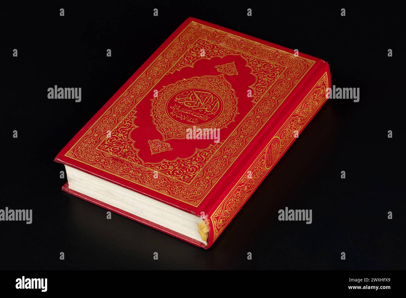 Muslim koran closed book  in red hard cover isolated on black studio background Stock Photo
