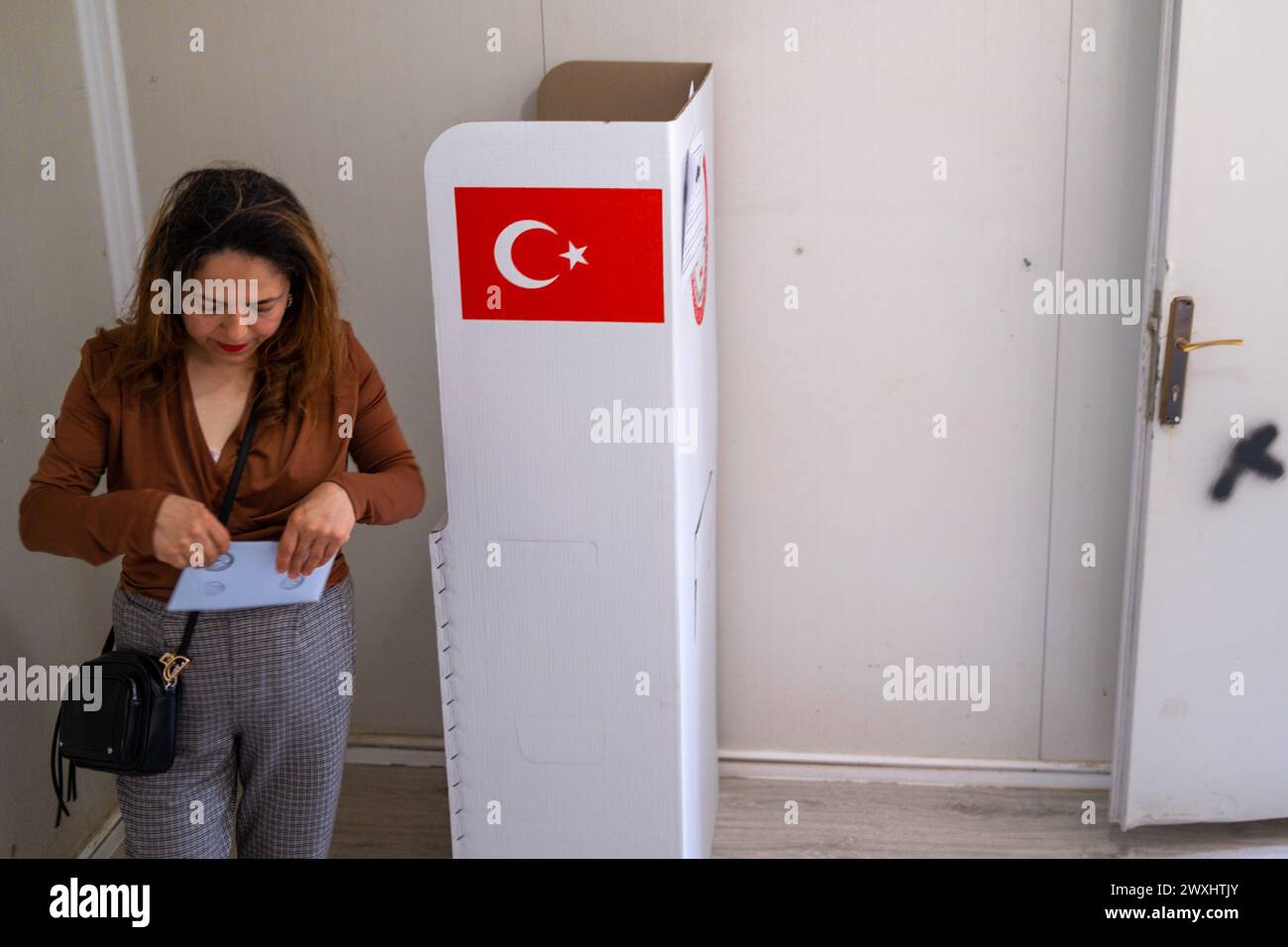 Hatay, Turkey. 31st Mar, 2024. A woman fixes an election envelope during the 2024 Turkish local elections. Voting for the local elections on March 31, 2024 has started in Antakya district of Hatay, an earthquake zone. People in the region are seen voting. Credit: SOPA Images Limited/Alamy Live News Stock Photo