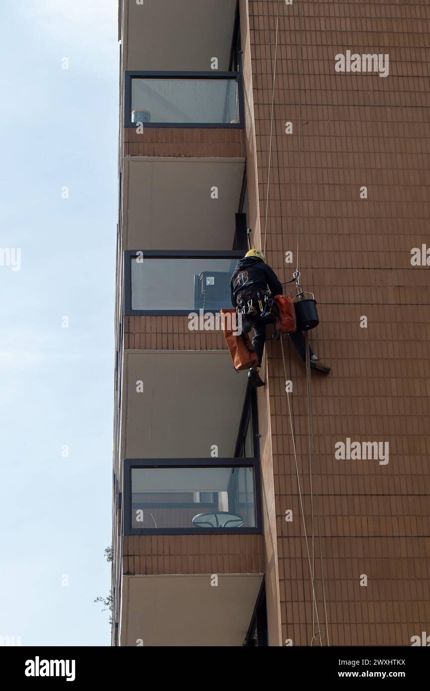 Vauxhall, London, UK. 26th March, 2024. A contractor with a head for heights hangs off a block of apartments next to Vauxhall Bridge doing maintenance. Credit: Maureen McLean/Alamy Stock Photo
