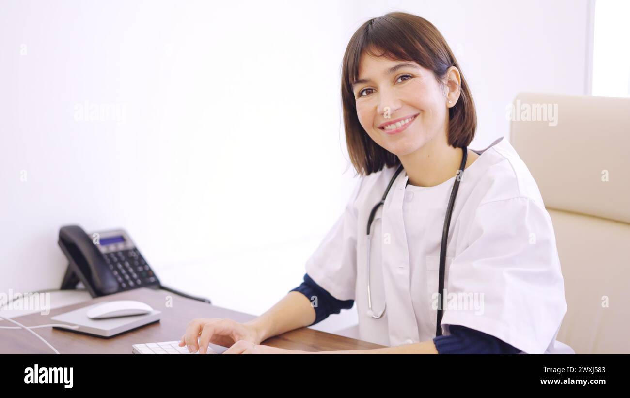 Female doctor using computer and smiling at camera Stock Photo