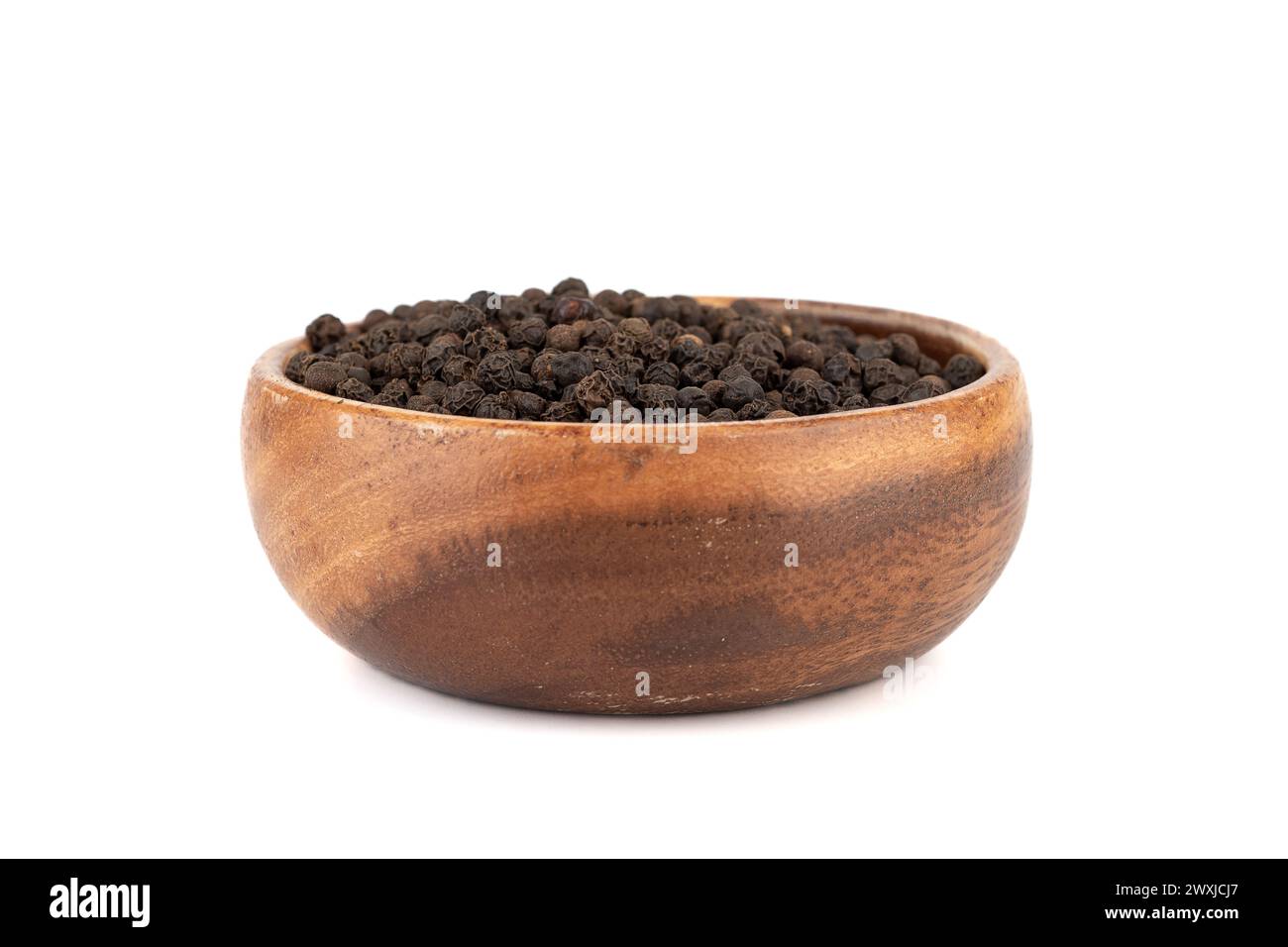 Wooden bowl with black unground pepper peas on white background. Food
