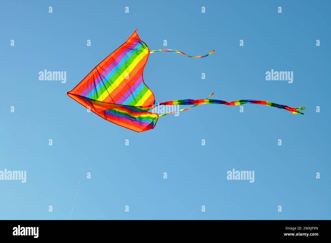 Colorful kite flying in clear sky Stock Photo