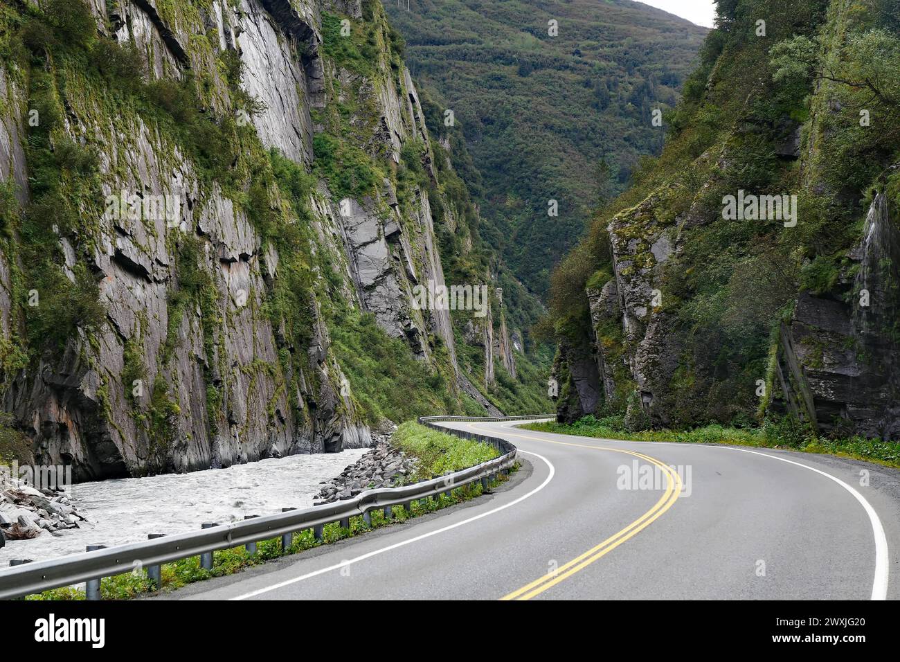 Road leads through a narrow canyon, high cliffs and Chugach Mountains, Thompson Pass, Richardson Highway, Alaska, USA Stock Photo