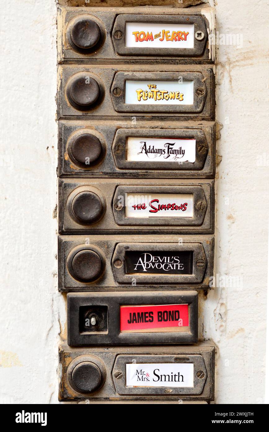 Old doorbells apartment block doorbell buttons and funny creative family name plates or nameplates of movies and cartoon titles outside block of flats front door in Sofia Bulgaria Stock Photo