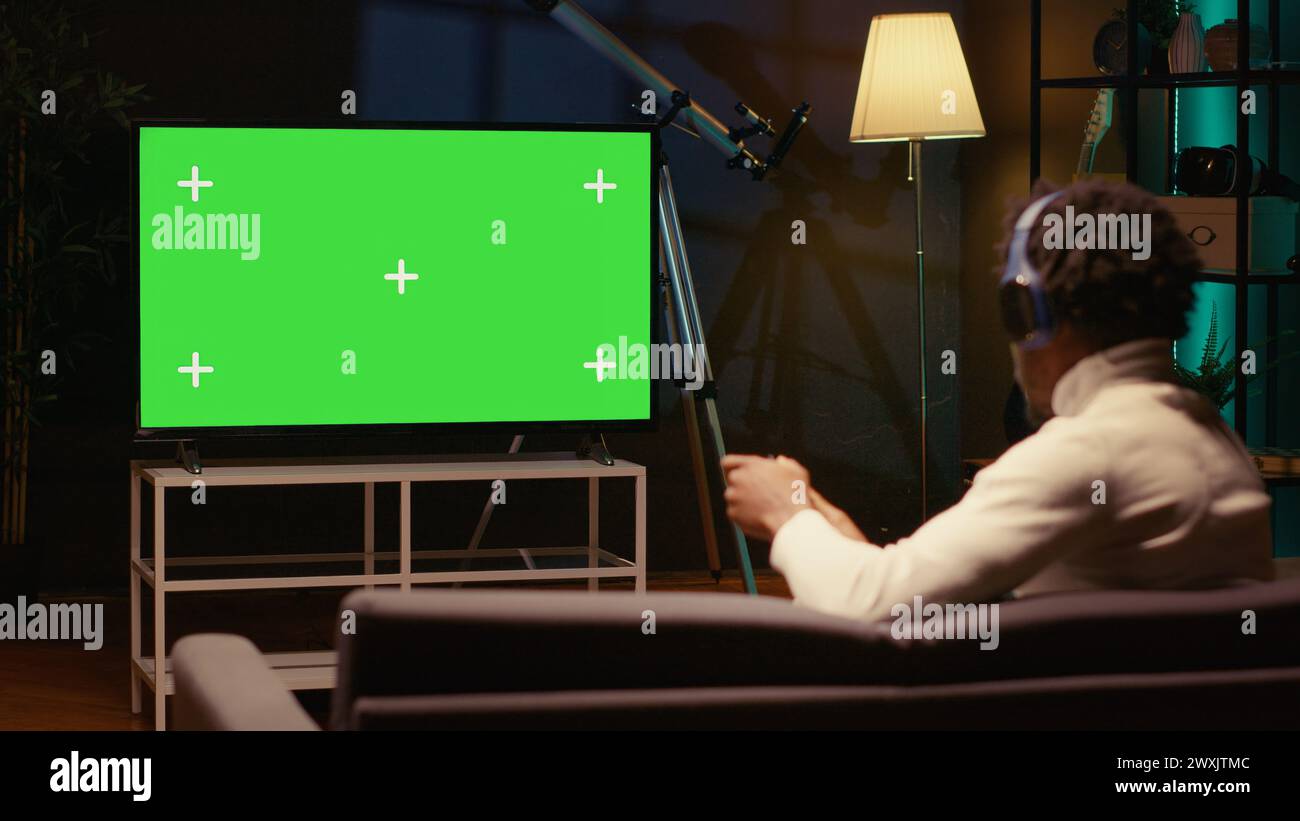 African american man sitting on couch at home, relaxing by playing ...