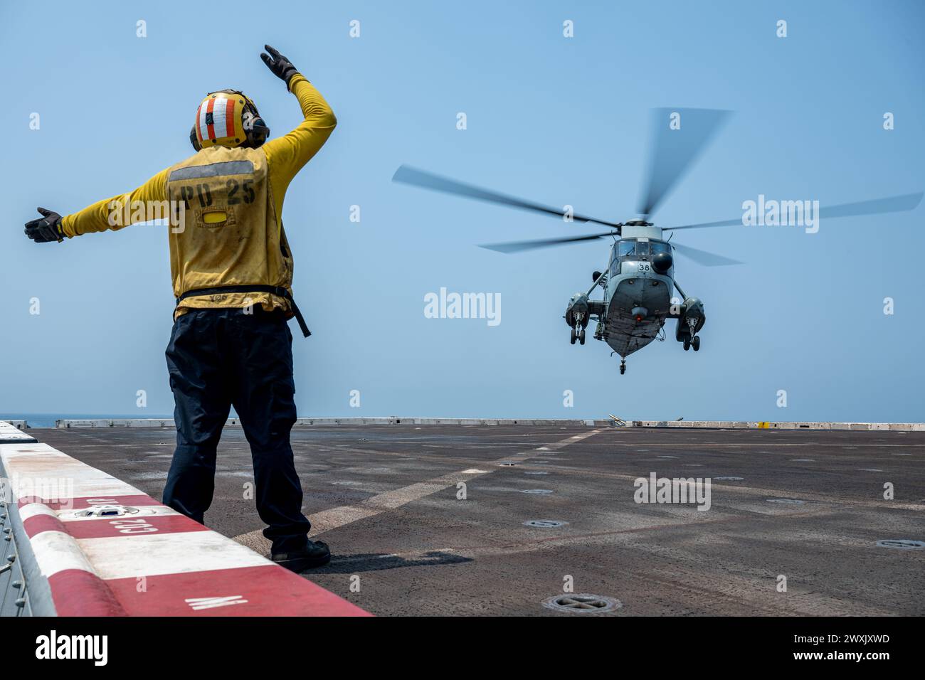 Aviation Boatswain’s Mate (Handling) 3rd Class Michael Aguilar, a native of Glendale, California, signals to a Republic of India Navy UH-3H Sea King on the flight deck of the San Antonio-class amphibious transport dock ship USS Somerset (LPD 25) while underway in the Bay of Bengal, Mar. 28, 2024, during Exercise Tiger TRIUMPH 2024. Tiger TRIUMPH is a U.S.-India tri-service amphibious exercise focused on humanitarian assistance and disaster relief readiness and interoperability. (U.S. Navy photo by Mass Communication Specialist 2nd Class Evan Diaz) Stock Photo