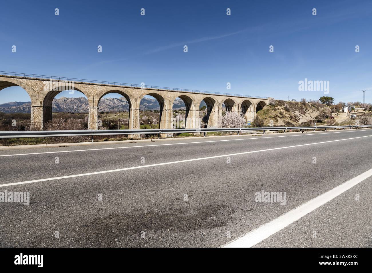 An old stone railway bridge with many arches next to a conventional road Stock Photo