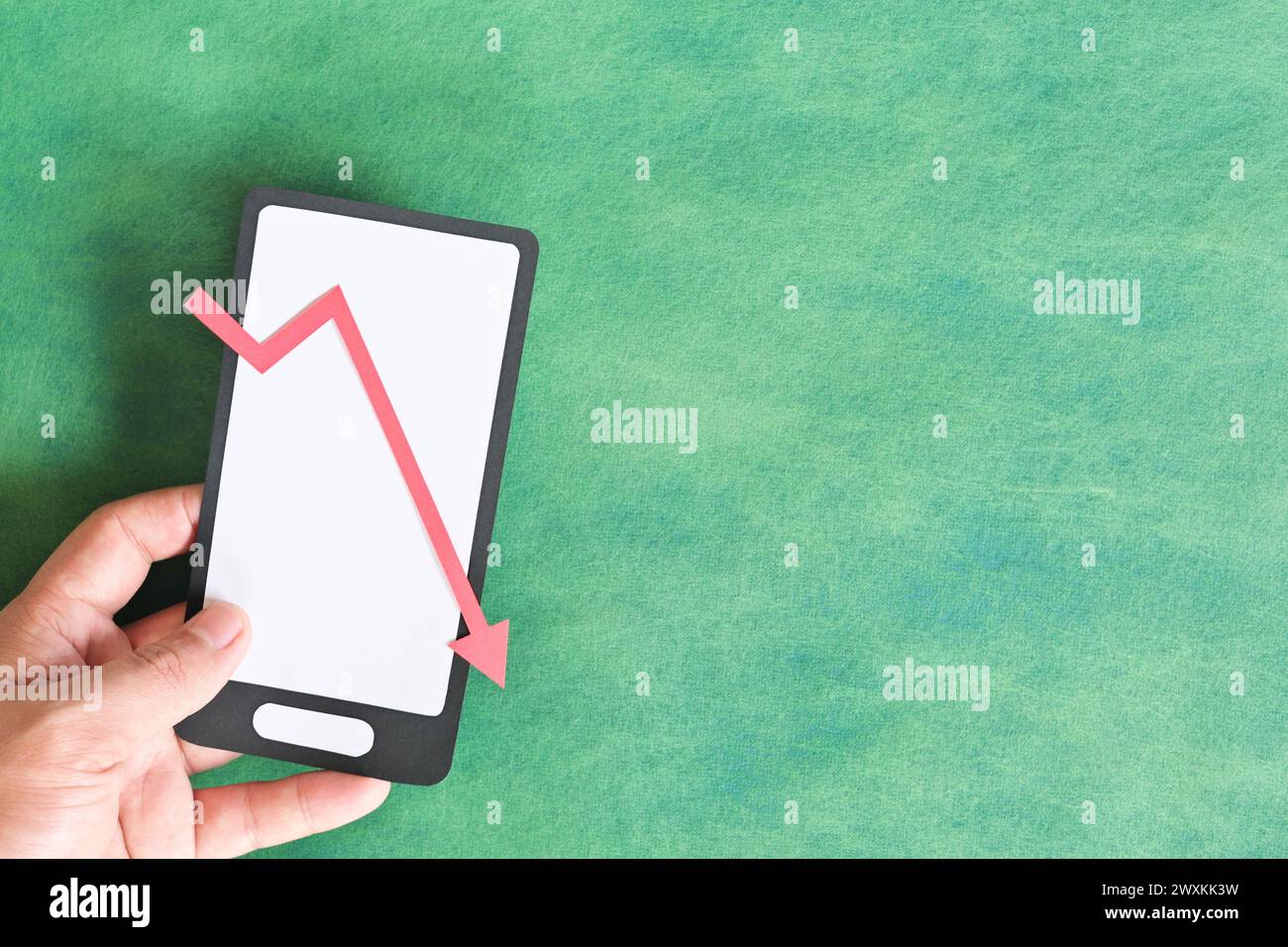 Male hand holding a mobile phone with red downward arrow. Investment and trading loss concept. Stock Photo
