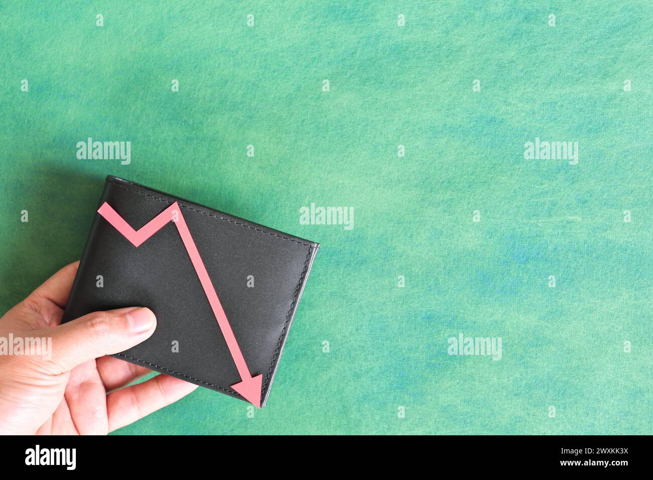 Male hand holding a wallet with red downward arrow. Money value currency depreciation and inflation concept. Stock Photo