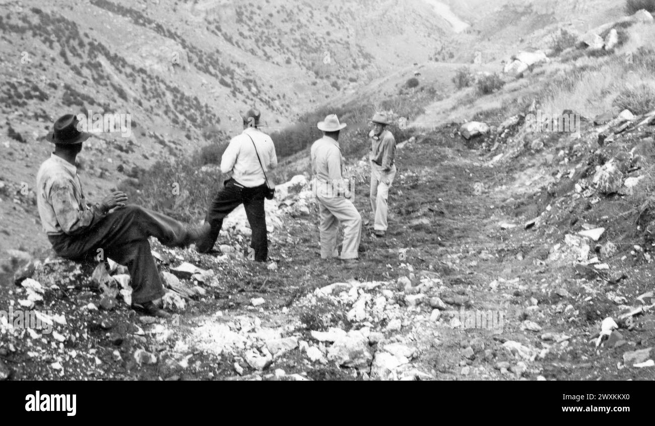Men in a rocky valley in Wyoming wearing cowboy hats, one man has a camera case ca. 1938-1948 Stock Photo