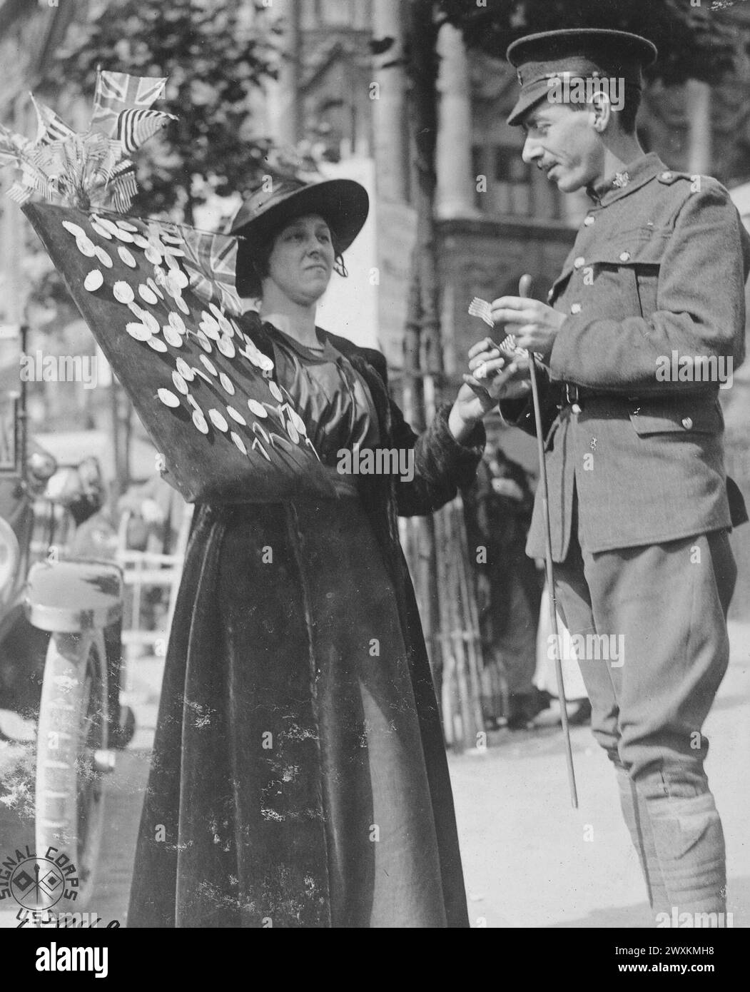 A woman selling American flags and badges to a Canadian soldier. Independence Day celebration in London England ca. 1918 Stock Photo