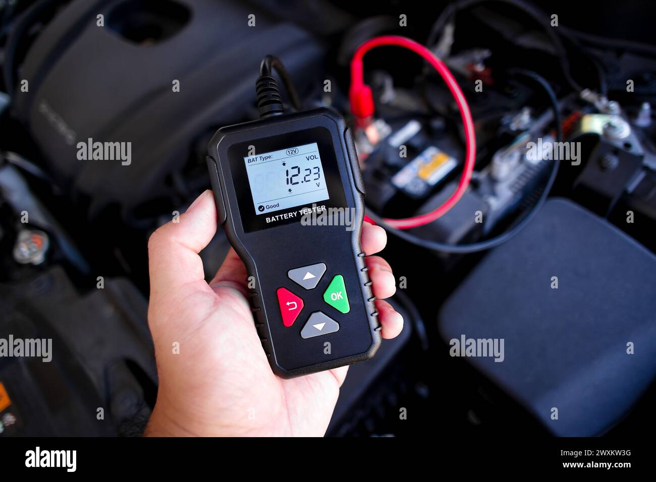 Battery tester in a auto mechanic hand for battery voltage or battery