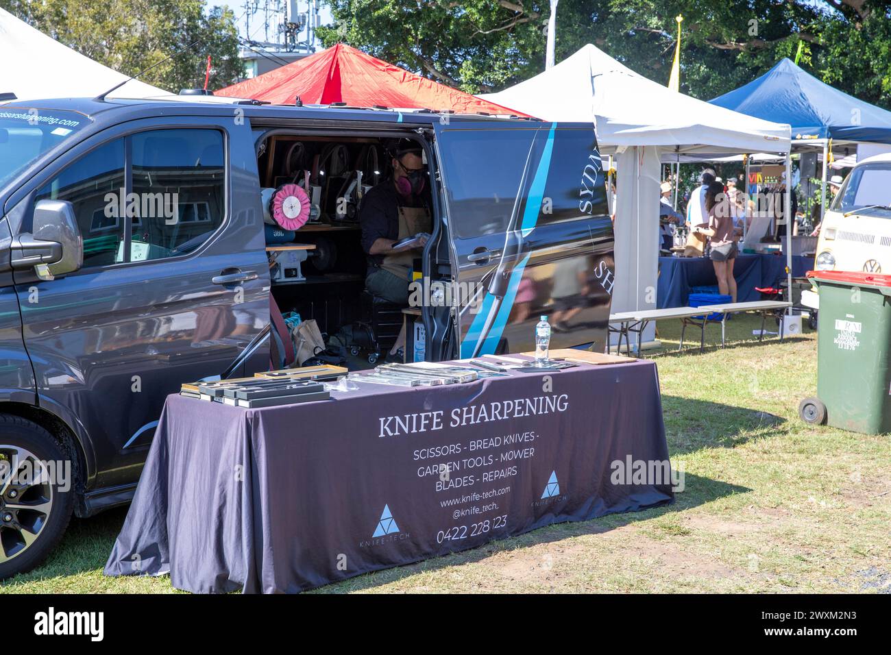 Knife sharpening, man working from his van offers knives sharpening service business at a Sydney Easter markets day, NSW,Australia Stock Photo
