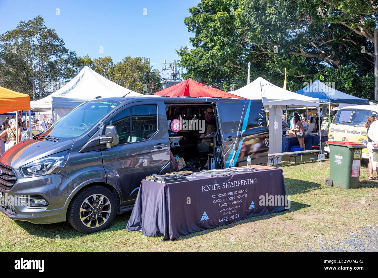Knife sharpening, man working from his van offers knives sharpening service business at a Sydney Easter markets day, NSW,Australia Stock Photo