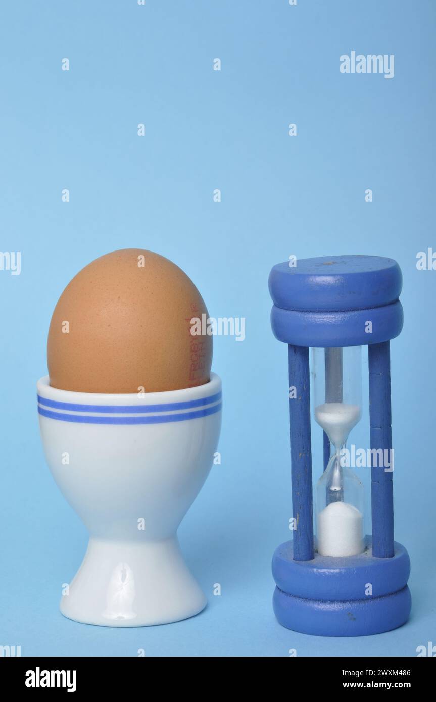 Boiled egg and hourglass on a blue background Stock Photo