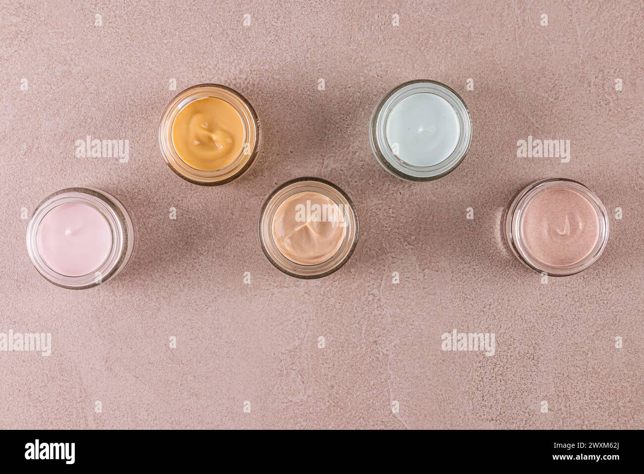 A set of glass jars with cosmetic cream of different colors for face ...