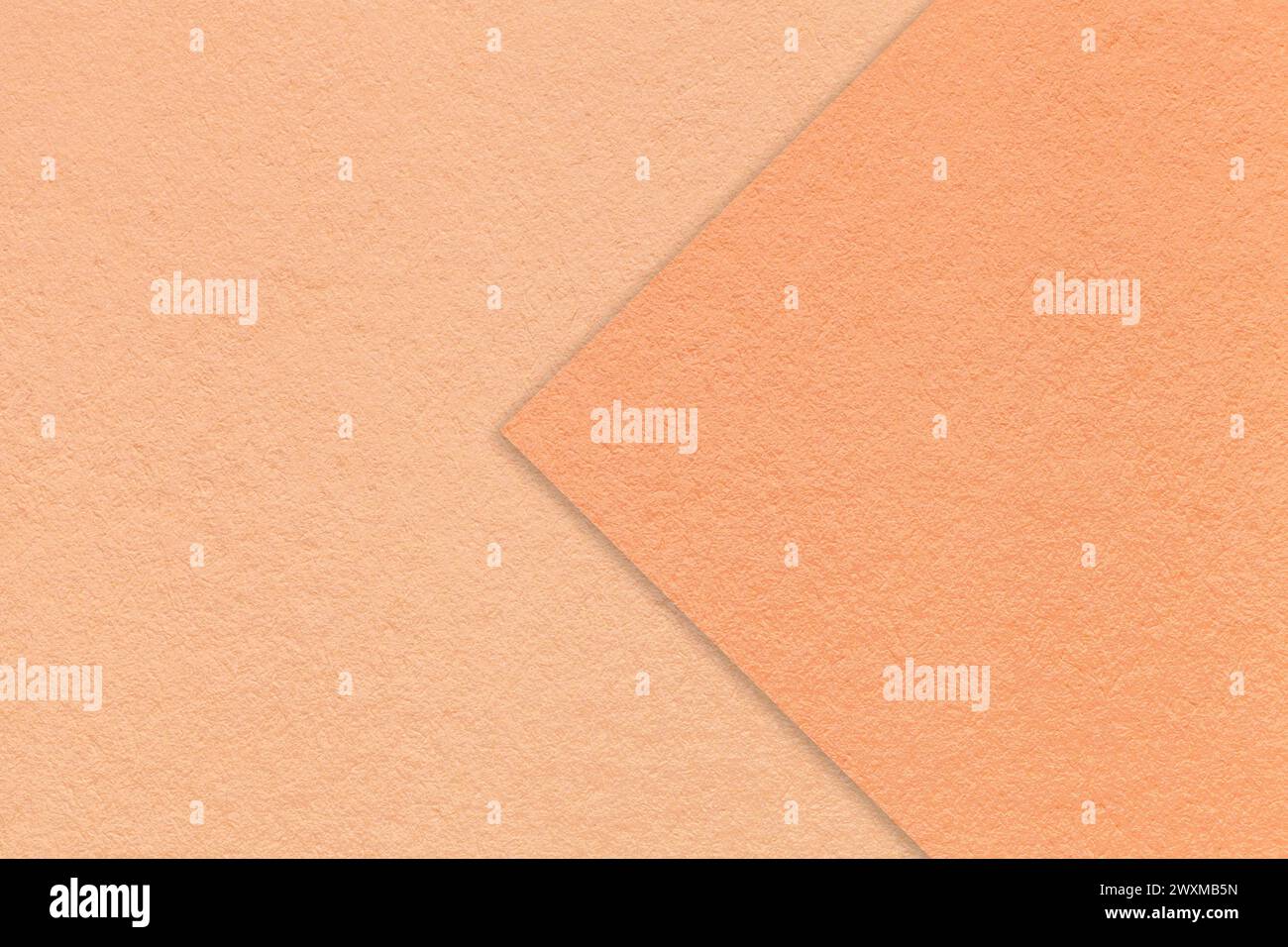 Color of the year 2024. Texture of peach fuzz paper background, half two colors with coral arrow, macro. Structure of dense craft cardboard. Felt abst Stock Photo