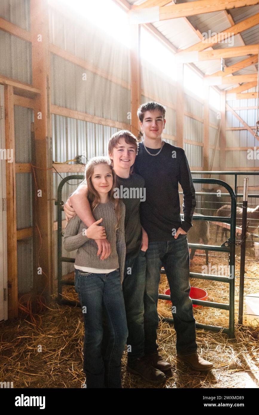 Three siblings posing in a barn. Stock Photo