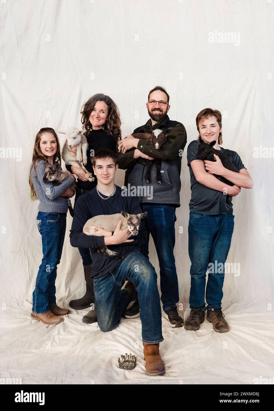 Farm family of five posing with their lambs. Stock Photo