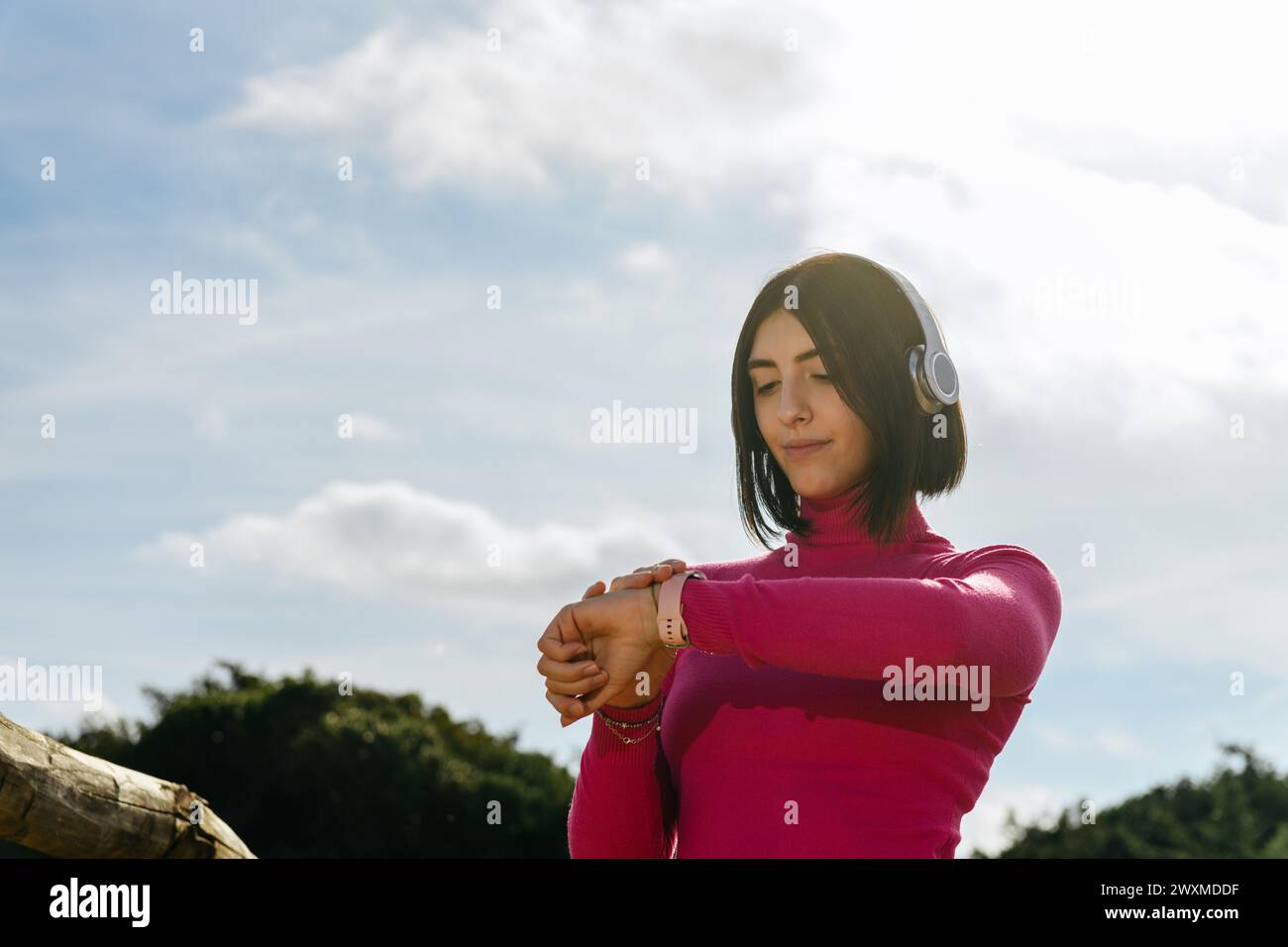 Young woman in headphone setting music on smartwatch Stock Photo