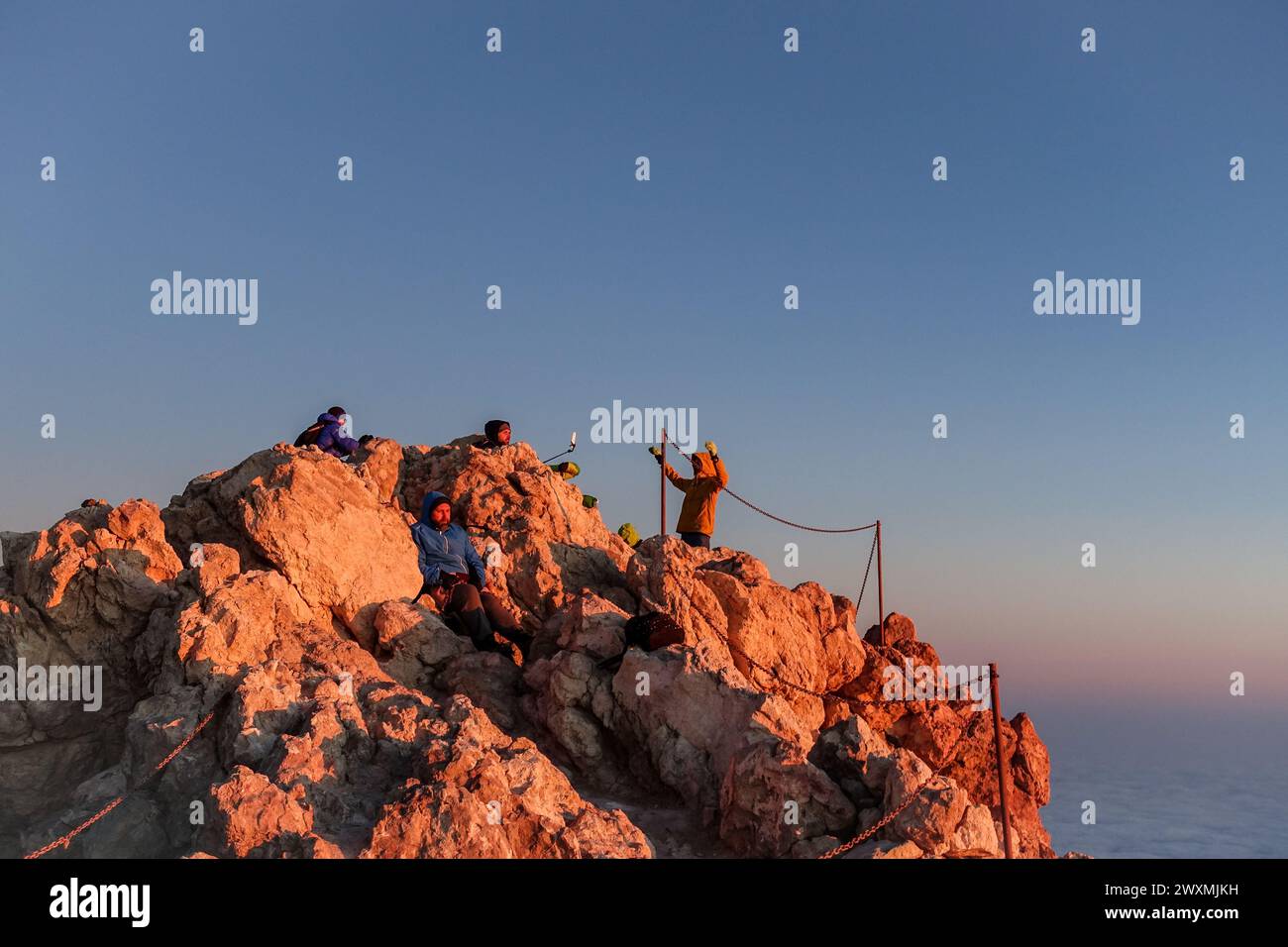Hikers standing on the summit of Mount Teide at sunrise enjoying panoramic views and taking photos Stock Photo