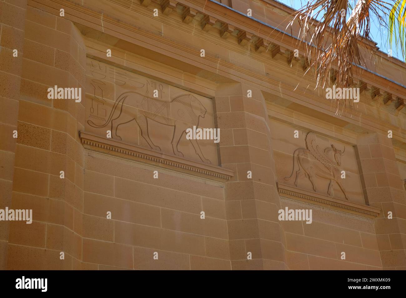 Bas-relief sandstone carvings Egyptian lion 1447 BC and an  Assyrian winged bull fourth century BC on the Mitchell Library façade, Sydney, Australia Stock Photo