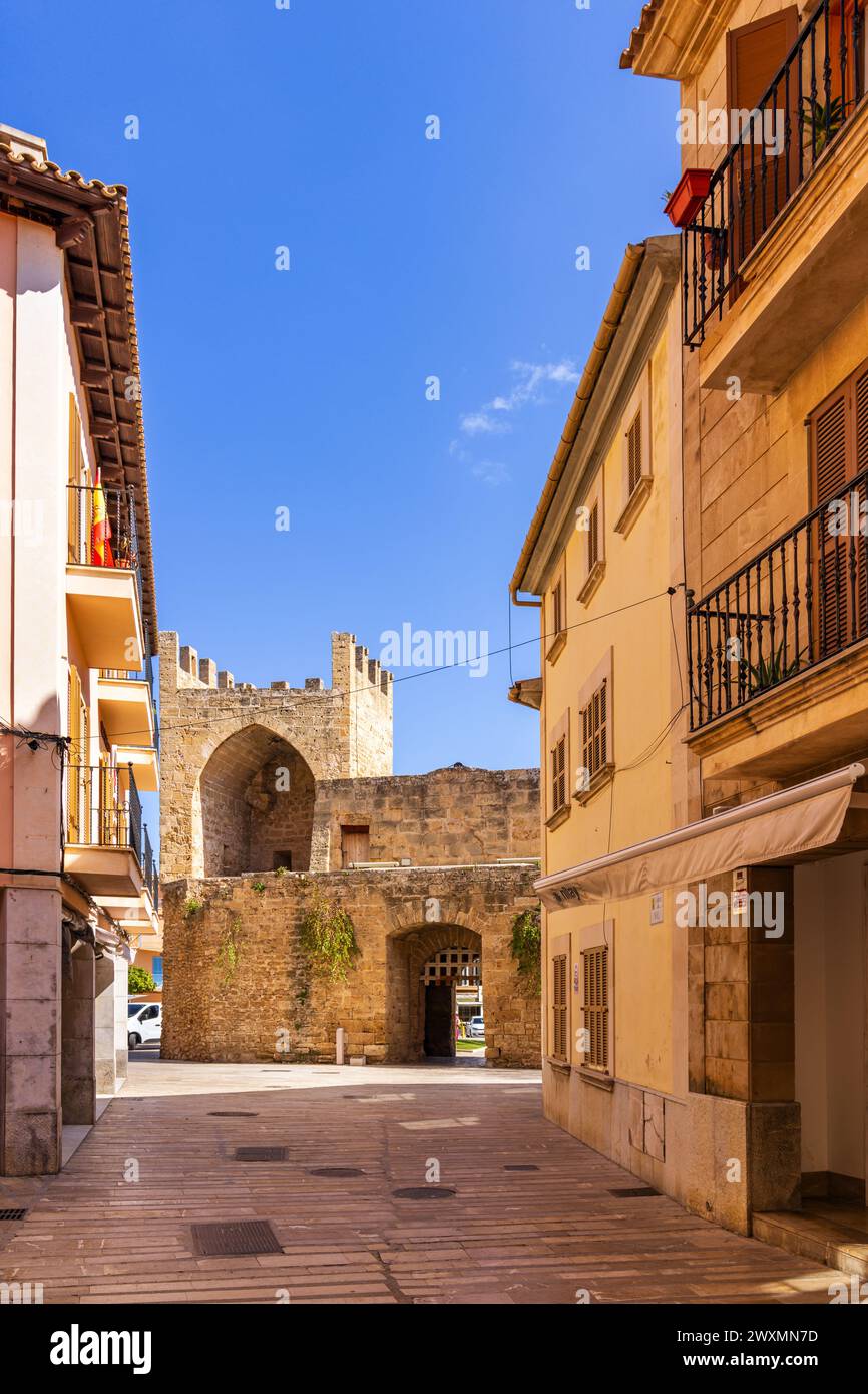 Street in Alcudia old town leading to the stone gate Porta del moll in Mallorca, Spain, Balearic Islands Stock Photo