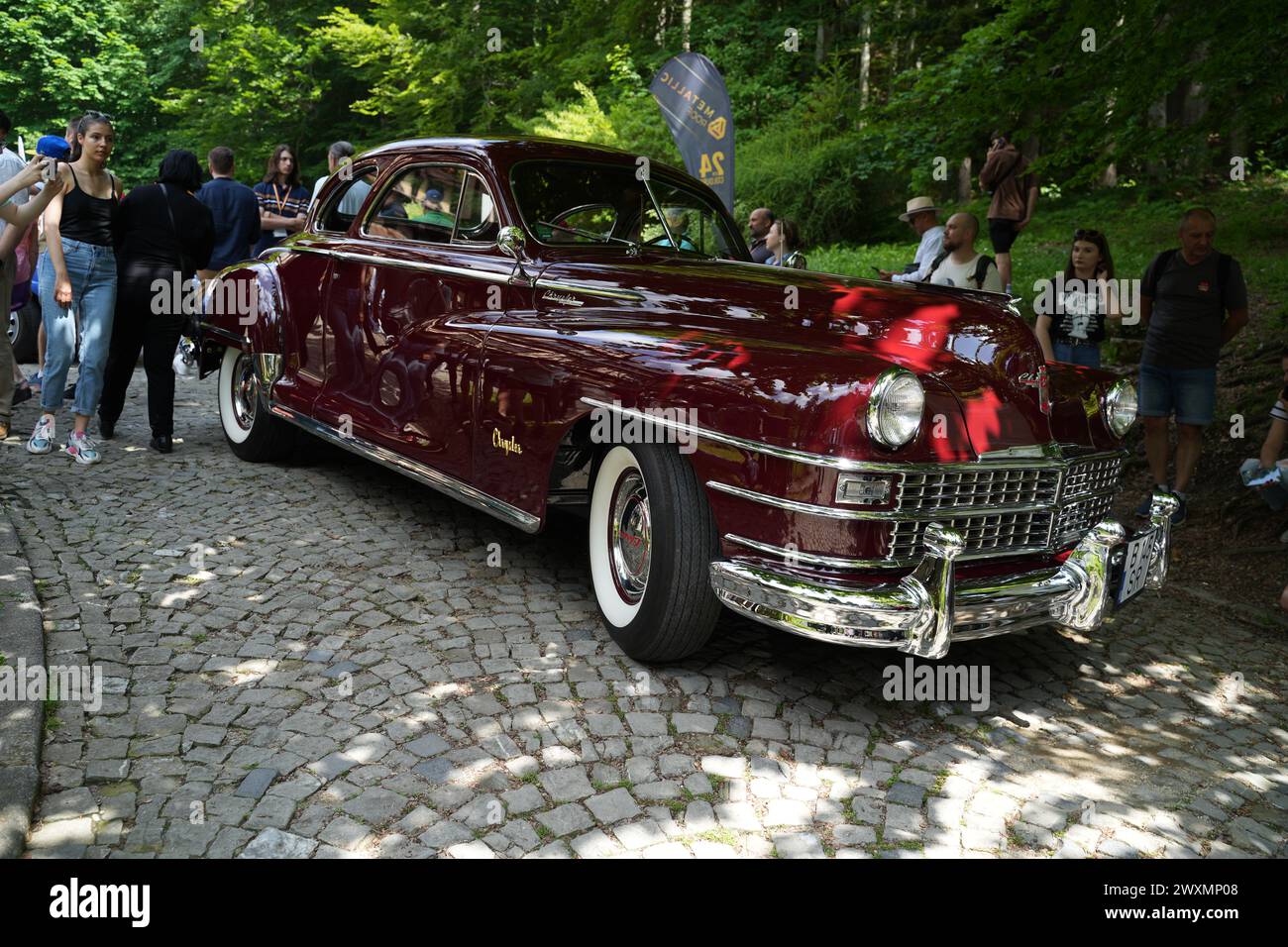 A maroon 1947 Chrysler Windsor Highlander Convertible parked on a cobblestone road Stock Photo