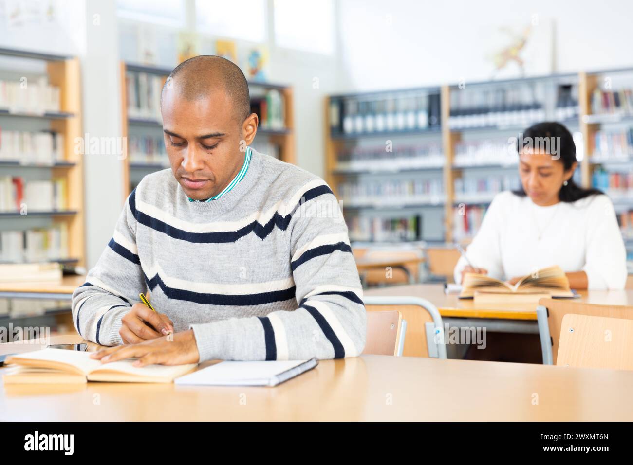 Young adult man studying in public library Stock Photo