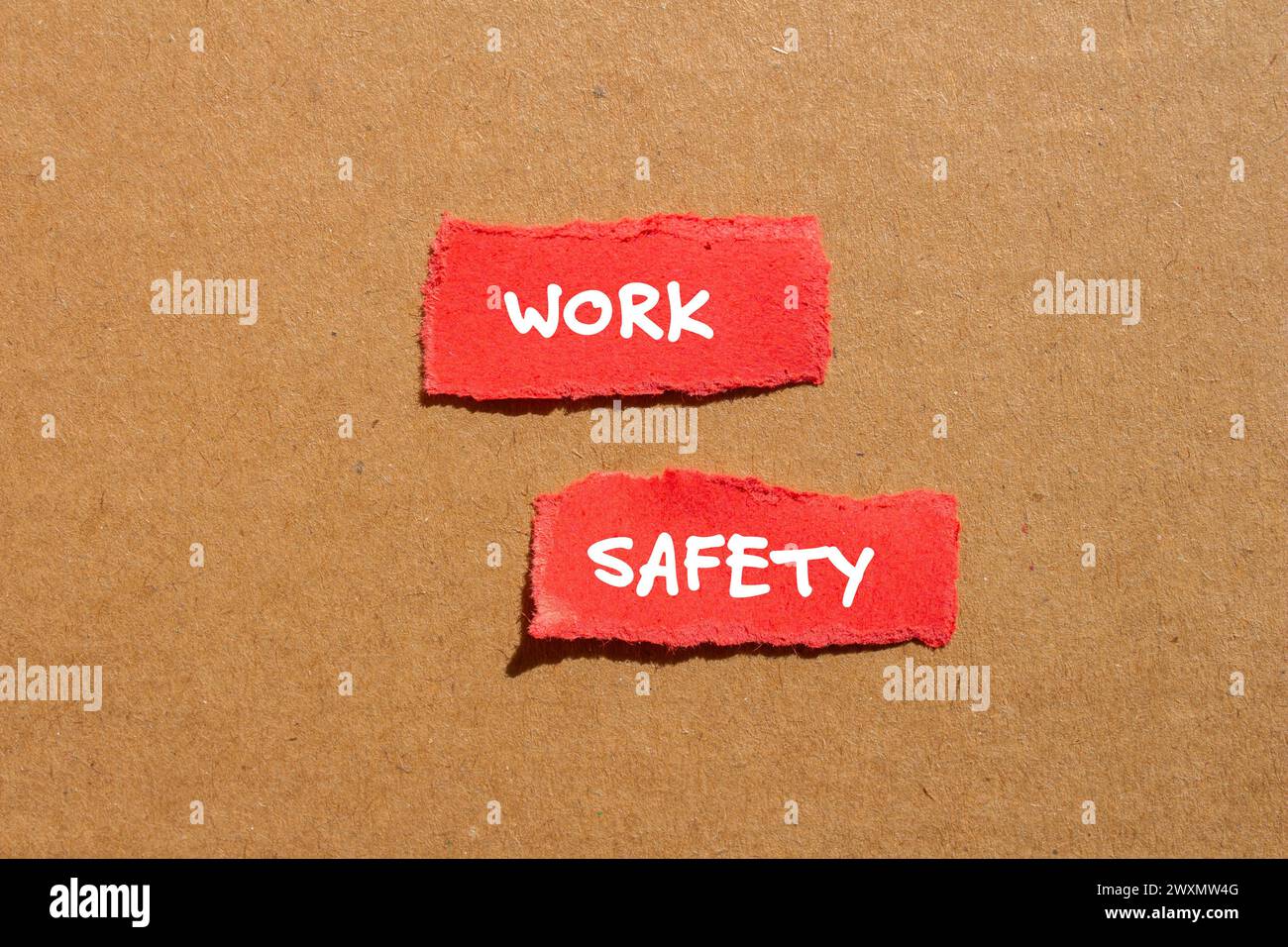 Work safety words written on red torn paper pieces with cardboard background. Conceptual business symbol. Copy space. Stock Photo