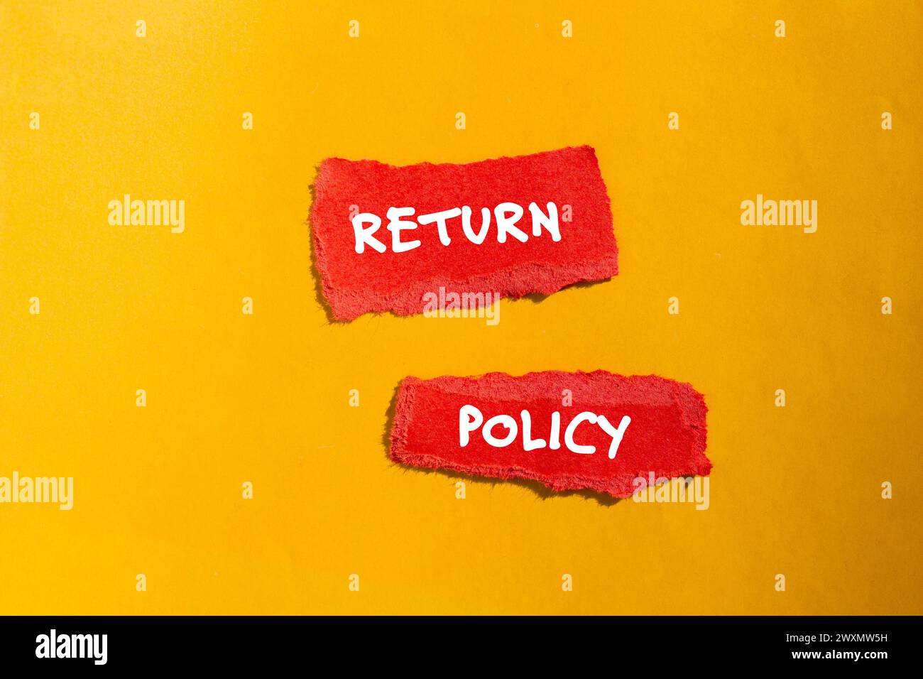 Return policy words written on red torn paper pieces with yellow