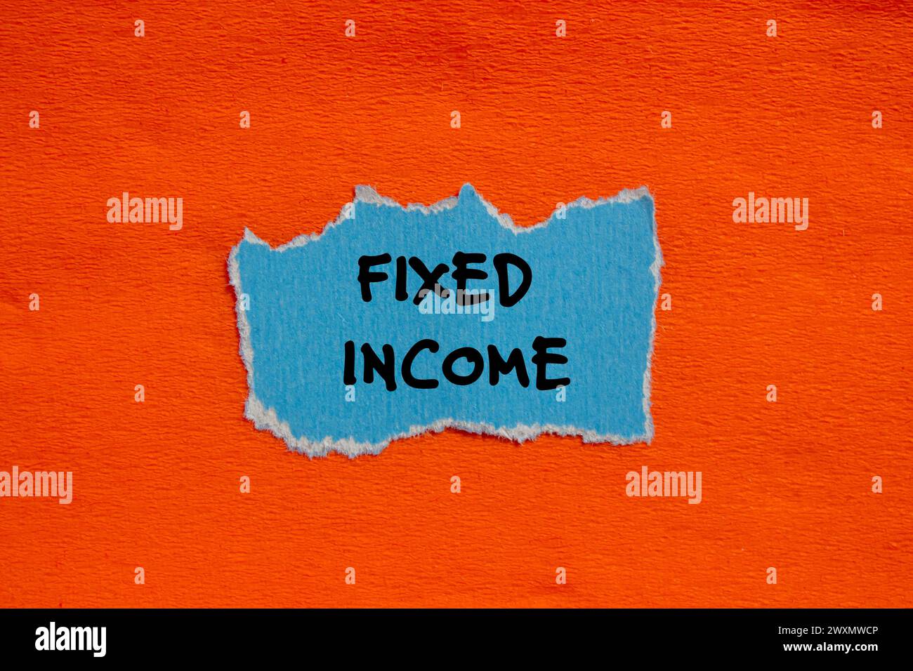 Fixed income words written on blue torn paper piece with orange ...