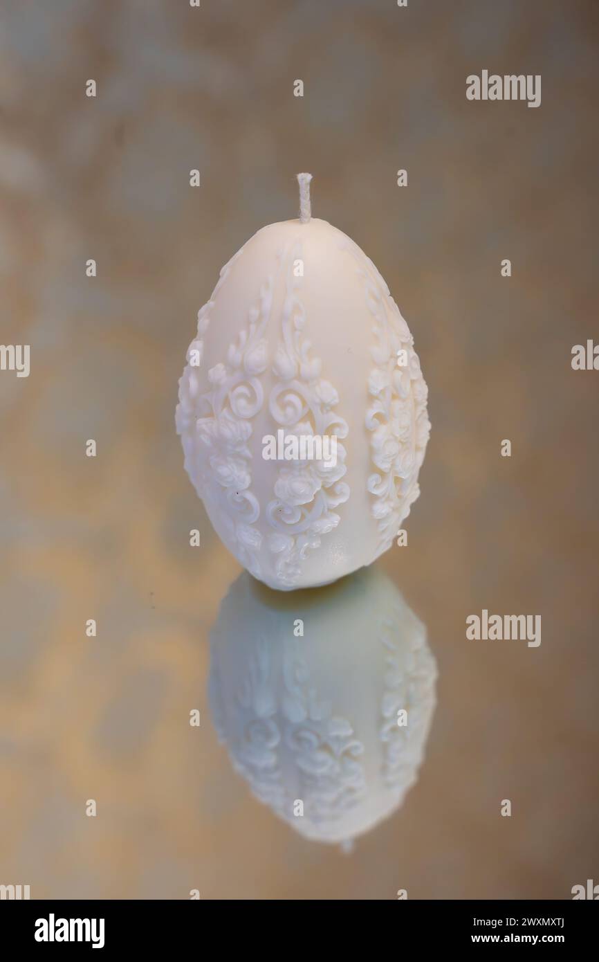 White easter egg soy wax candle. Mirror background Stock Photo
