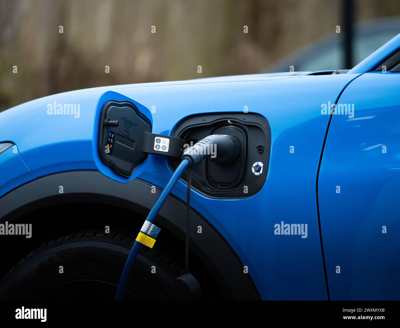 Recharging Ford Mustang Mach-E with the plug in the car socket close up. Electric mobility as an alternative. The EV uses modern charging technology. Stock Photo