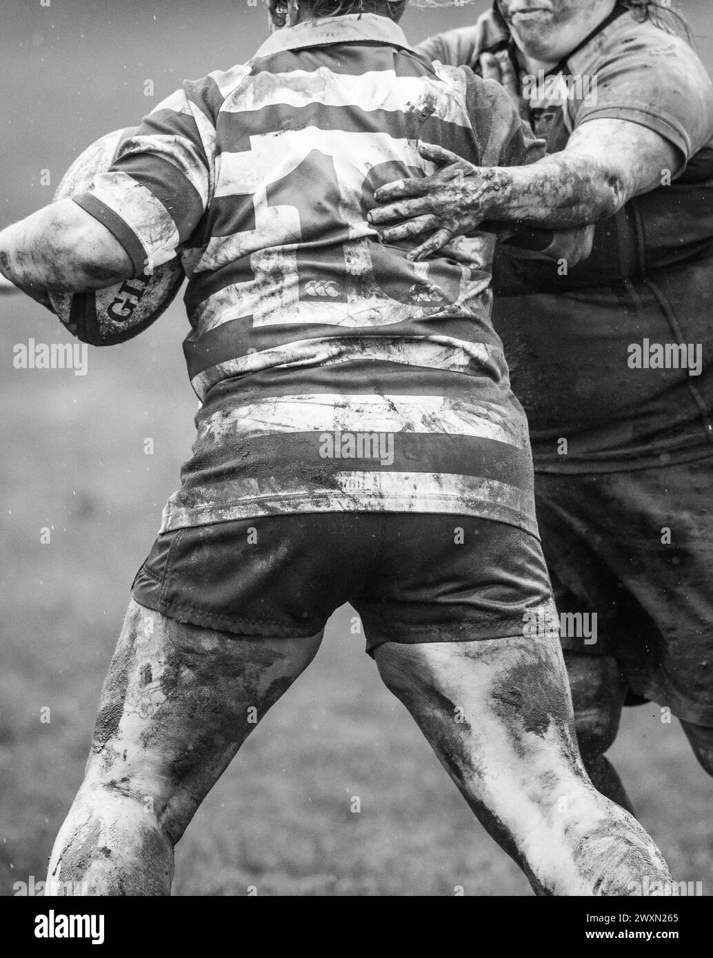 English amateur rugby union woman game playing in wet and muddy conditions and a number 18 shirt. Stock Photo