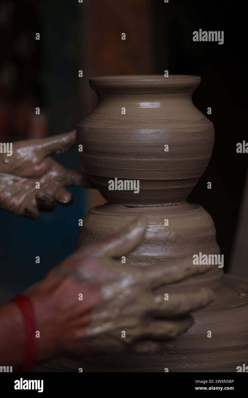 The potter works on a pottery wheel to made of soft colored clay, retro style toned Clay pots with hand and equipment Stock Photo