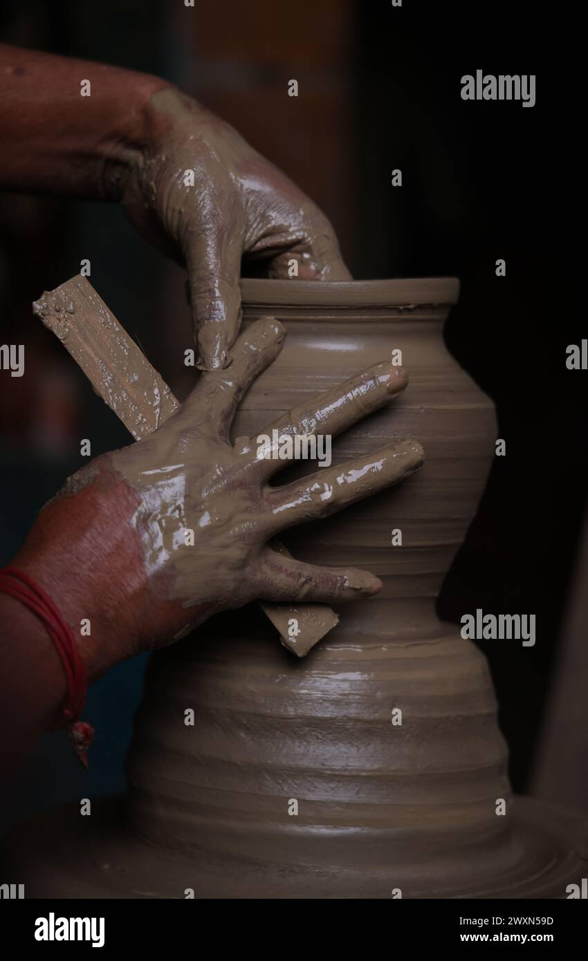 The potter works on a pottery wheel to made of soft colored clay, retro style toned Clay pots with hand and equipment Stock Photo