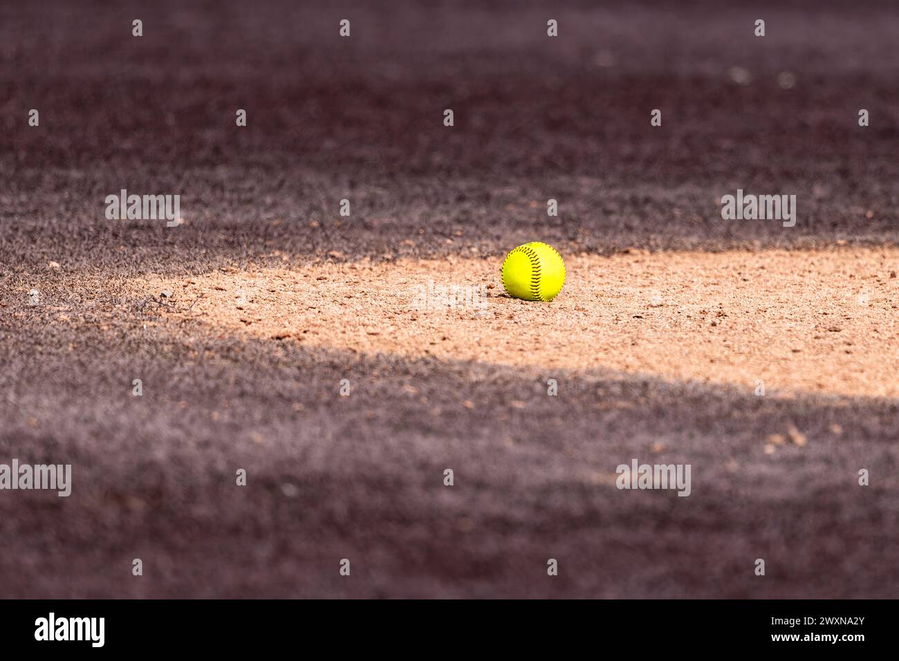 Optic yellow softball on clay pitchers circle with brown synthetic turf Stock Photo