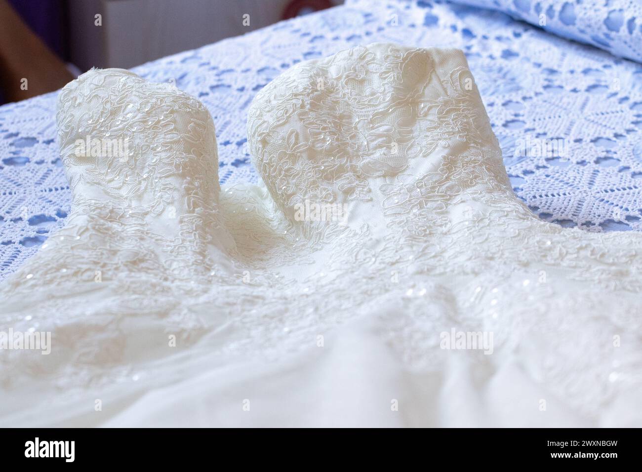 exquisite lace embroidery adorns the bodice of a bridal gown, laid out in preparation for the momentous day Stock Photo