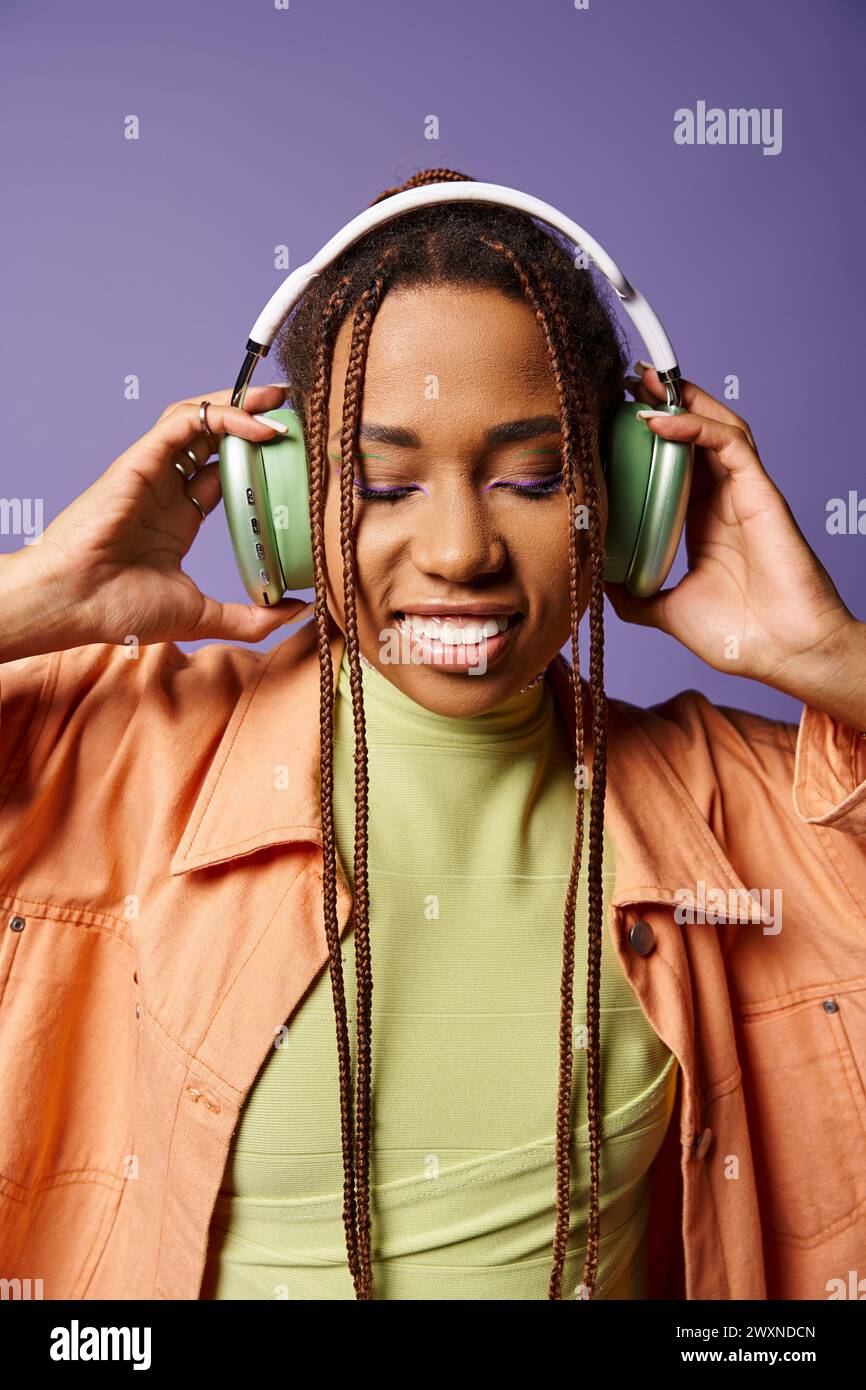 joyful african american woman in vibrant attire with wireless ...